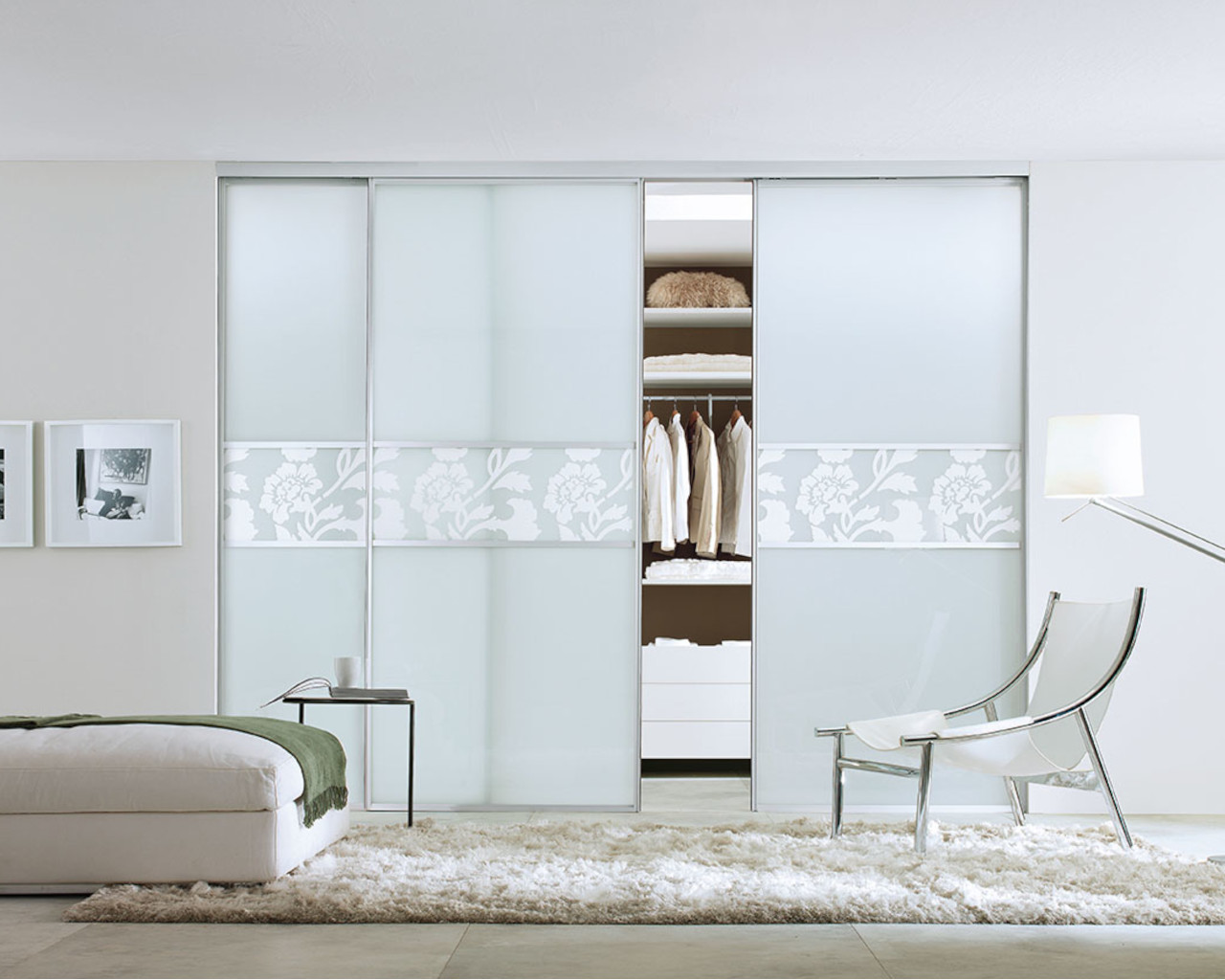 Schiebetüren auf Maß Helles Schlafzimmer mit eleganten weißen Möbeln zum Sitzen und praktischen Schiebetüren vor einem offenen Schranksystem, die für eine luftige und einladende Umgebung sorgen.