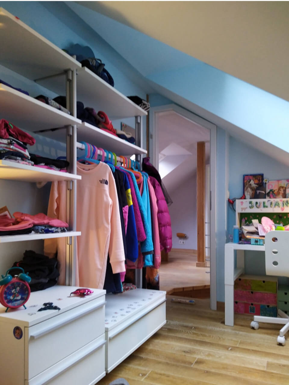 Kundenbeispiel: Schranksystem im Kinderzimmer unter Dachschräge mit Hängemöglichkeiten, offenen Regalen und Schubladen – kindgerechte Stauraumlösung